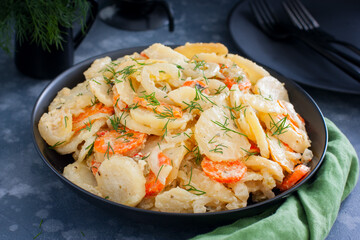 Baked potatoes with carrots in the oven on a black dish, selective focus