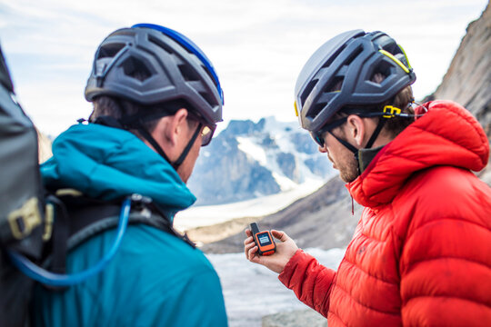 Two climbers use a GPS to navigate mountain terrain.