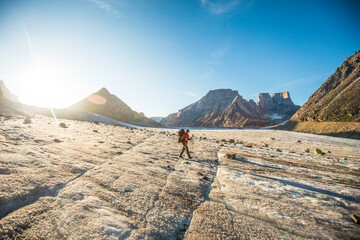 Backpacker exploring large glacier and mountains on Baffin Island.