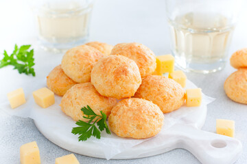 Baked cheese balls on white board with glasses of white wine, horizontal