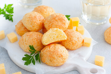 Baked cheese balls on white board with glasses of white wine, horizontal