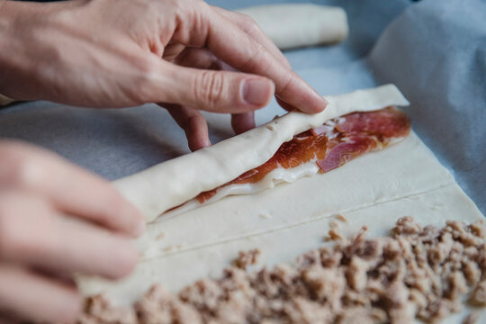 Crop person making meat rolls