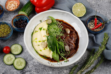 Veal cheeks in gravy with potatoes and cabbage, decorated with herbs