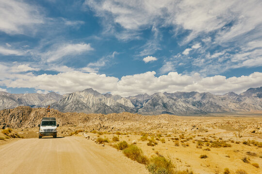 Young woman on roof of camper van on road in northern California.