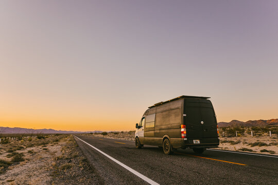 Camper van on isolated highway during sunset in desert of Mexico.