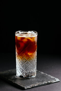 glass of alcoholic coctail with ice on black background