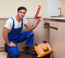 Young repairman working at the kitchen