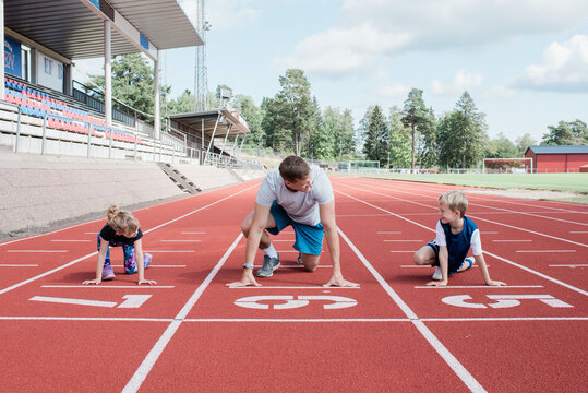 Father along with his kids getting ready to run on running track