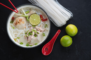 Bowl of traditional vietnamese Pho Ga soup, flatlay over black stone background, horizontal shot