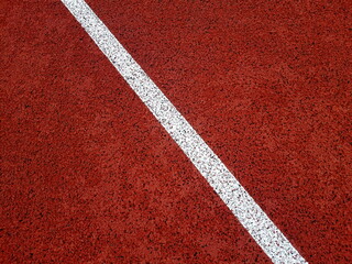White lane on a red stadium running track. Close up curve running track rubber. 