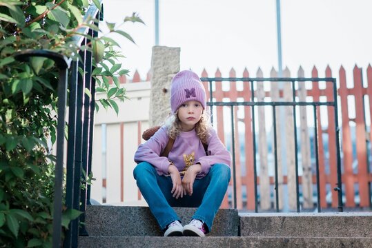 young girl sitting on a step looking thoughtful waiting for school