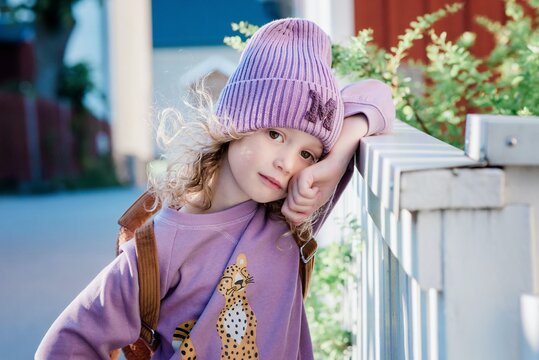 portrait of a beautiful young girl leaning on a fence at school