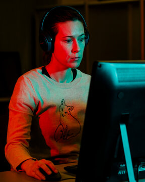 Portrait of a woman with headphones focused on a desktop computer