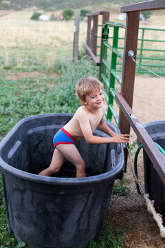 Boy playing in horse trough in the summer in his underwear