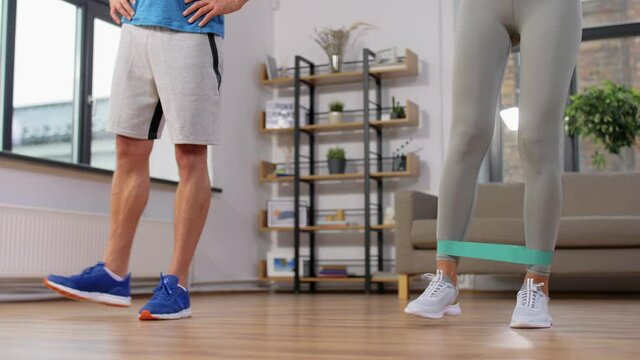 sport, fitness, lifestyle and people concept - smiling man and woman exercising with resistance bands at home
