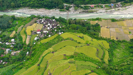 Fototapeta premium Village and river in a mountain gorge, top view. Rice cultivation in the North of the Philippines, aerial view. Tropical landscape, river and rice fields. Landscape, villages in the highlands.
