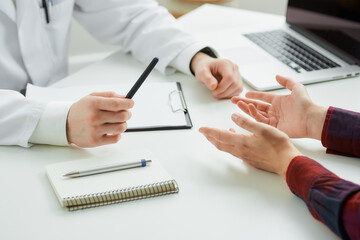 A close photo of the hands of a female patient and a doctor at an appointment in a hospital. A...