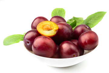 Violet fresh ripe plums in the white plate, light background