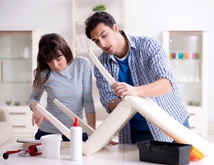Wife helping husband to repair broken chair at home