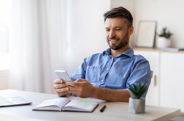 Handsome Young Businessman Using Smartphone At Workplace In Office, Checking New App
