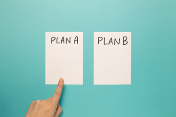 Choose Plan A with finger on blue background. Business plan, choice, change, dilemma concept. top view © Sanga