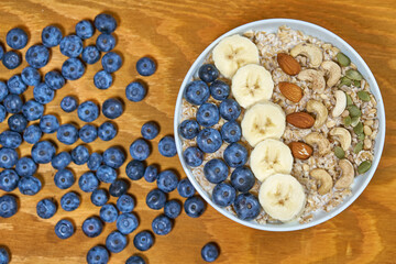 Delicious oatmeal and blueberry breakfast with bananas. Walnut and almond decor. Health food. Correct breakfast. High quality photo