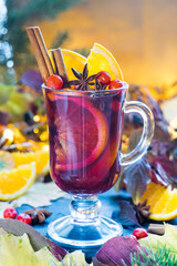 Mulled red wine with spices and orange slices on a wooden rustic table. Selective focus.