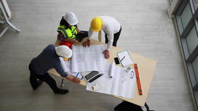 Team of engineers and architects working, planing, measuring layout of building blueprints in construction site. top view