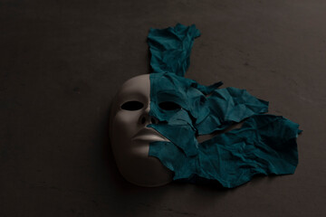 White theater mask on a black background covered with leather flaps. Psychic symbol of overlapping...