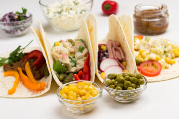 Canned corn and green peas in glass bowls. Vegetable tacos filled with various vegetables.