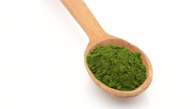chlorella or spirulina powder superfoods in wooden spoon rotation to left