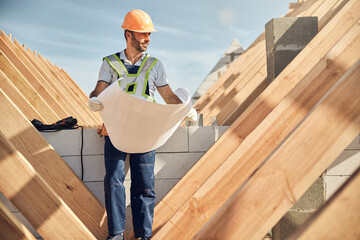 Satisfied construction site worker checking the blueprint of a building