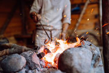Fototapeta premium Fire crackling in blacksmith workshop of forging metal. Anonymouse craft smith create objects from wrought iron or steel with helper.