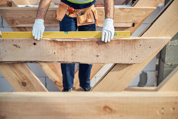 Construction site worker in gloves using a level spirit ruler