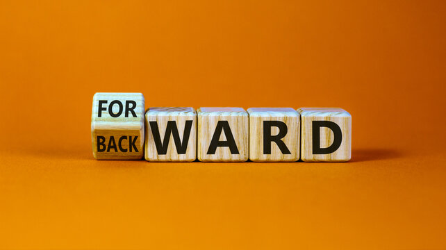 Turned a cube and changed the word 'backward' to 'forward' on wooden cubes. Beautiful orange background, copy space. Business concept.