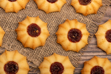Homemade pastry cookies with jam on a background of homespun fabric with a rough texture, close-up, selective focus.