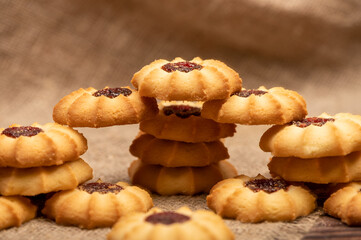 Fototapeta na wymiar Homemade pastry cookies with jam on a background of homespun fabric with a rough texture, close-up, selective focus.