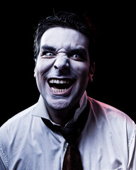 Dark studio photo of a male zombie or vampire with dark hair on black background.