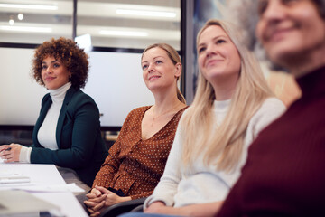 Line Of Businesswomen In Modern Office Listening To Presentation By Colleague