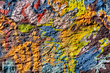 Multicolored paint on a rough wall. Abstract illustration on stucco.