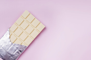 White chocolate in foil on pink background