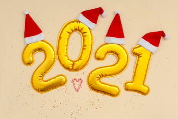 Happy New Year Golden digits 2021 numbers with christmas hat on beige background with confetti.