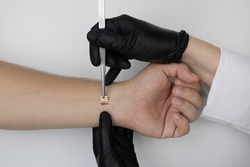 The cosmetic surgeon made a small incision to insert the chip into the patient's arm. Biotechnology, electronic documents and technological future concept