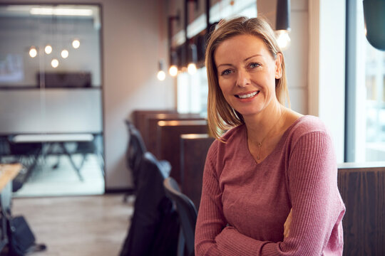 Head And Shoulders Portrait Of Smiling Mature Businesswoman  Working In Modern Office
