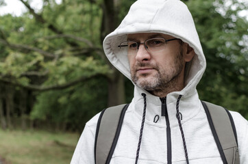 Naklejka na ściany i meble Portrait of a middle-aged man in a hooded weater in the forest