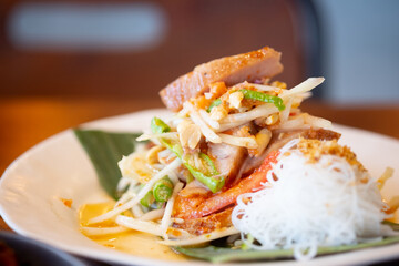 Thai spicy green papaya salad mix grilled pork neck served with rice vermicelli