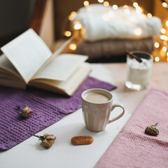 Autumn or winter still life. Coffee cup, candle, flowers, book and knitted sweaters. Hygge lifestyle, cozy autumn mood. Flat lay