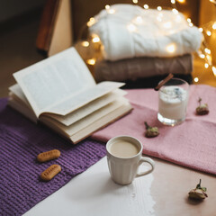 Autumn or winter still life. Coffee cup, candle, flowers, book and knitted sweaters. Hygge lifestyle, cozy autumn mood. Flat lay
