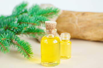 Spruce essential oil in a bottle, with fresh spruce twigs in the background. Aromatherapy, spa, homeopathy.