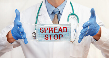 The doctor is wearing a protective mask with the inscription SPREAD STOP